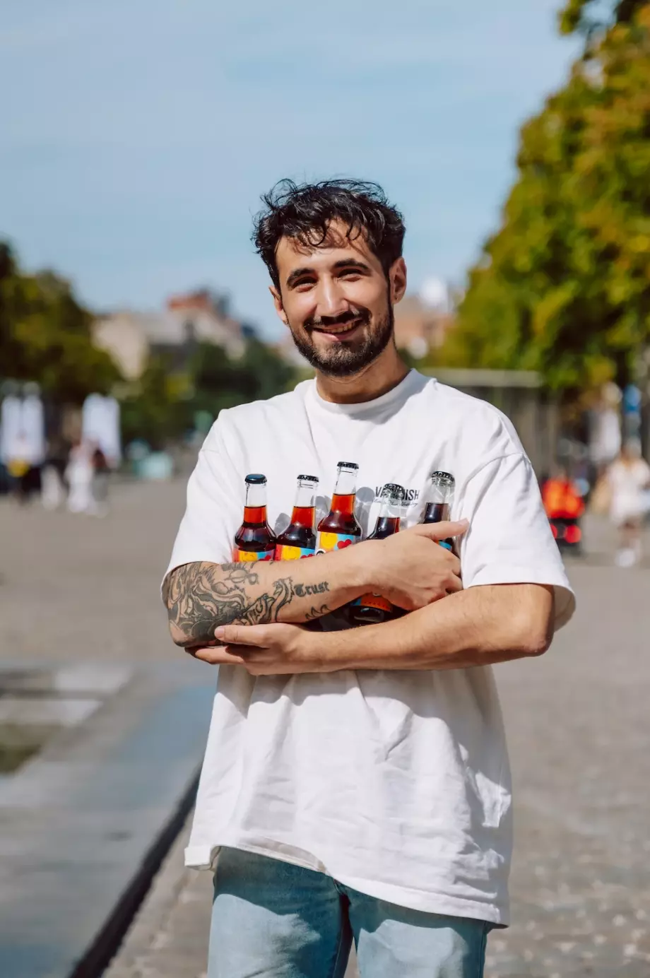 Homme souriant avec des bouteilles de Paola Cola dans les bras