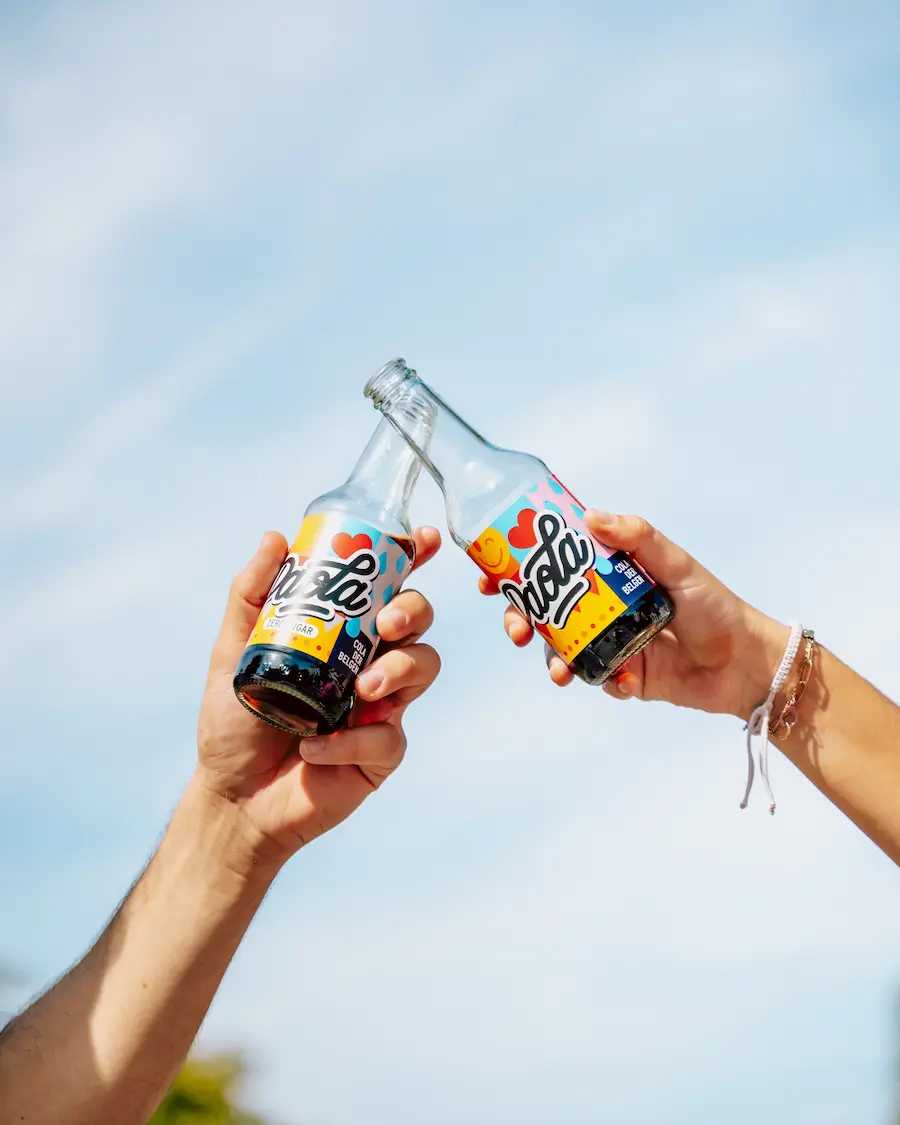 Deux bouteilles de Paola Cola qui trinquent sous le ciel bleu